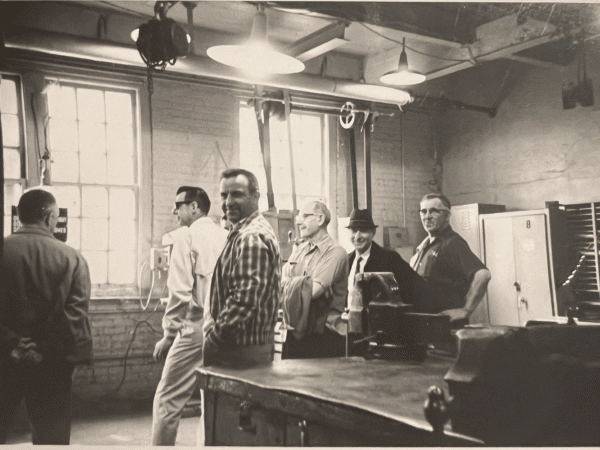 Sean Sullivan's grandfather smiles at the camera around other workers at South Works.