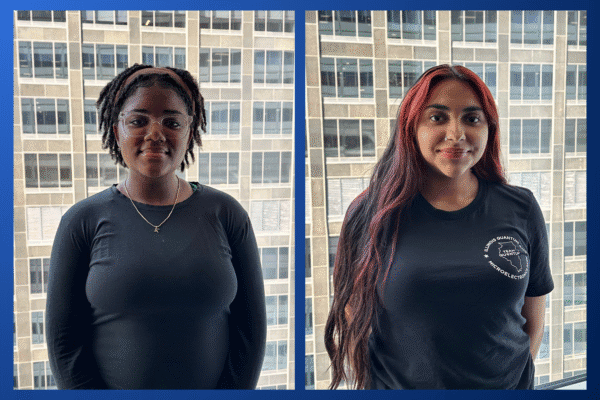 Side-by-side portraits of Illinois Quantum and Microelectronics Park interns. On the left, Kanyn, wearing glasses, a black long-sleeve shirt, and a gold necklace, stands in front of a windowed city building backdrop. On the right, Mikayla, with long dark hair streaked with red, wears a black IQMP T-shirt, also in front of the same building backdrop.