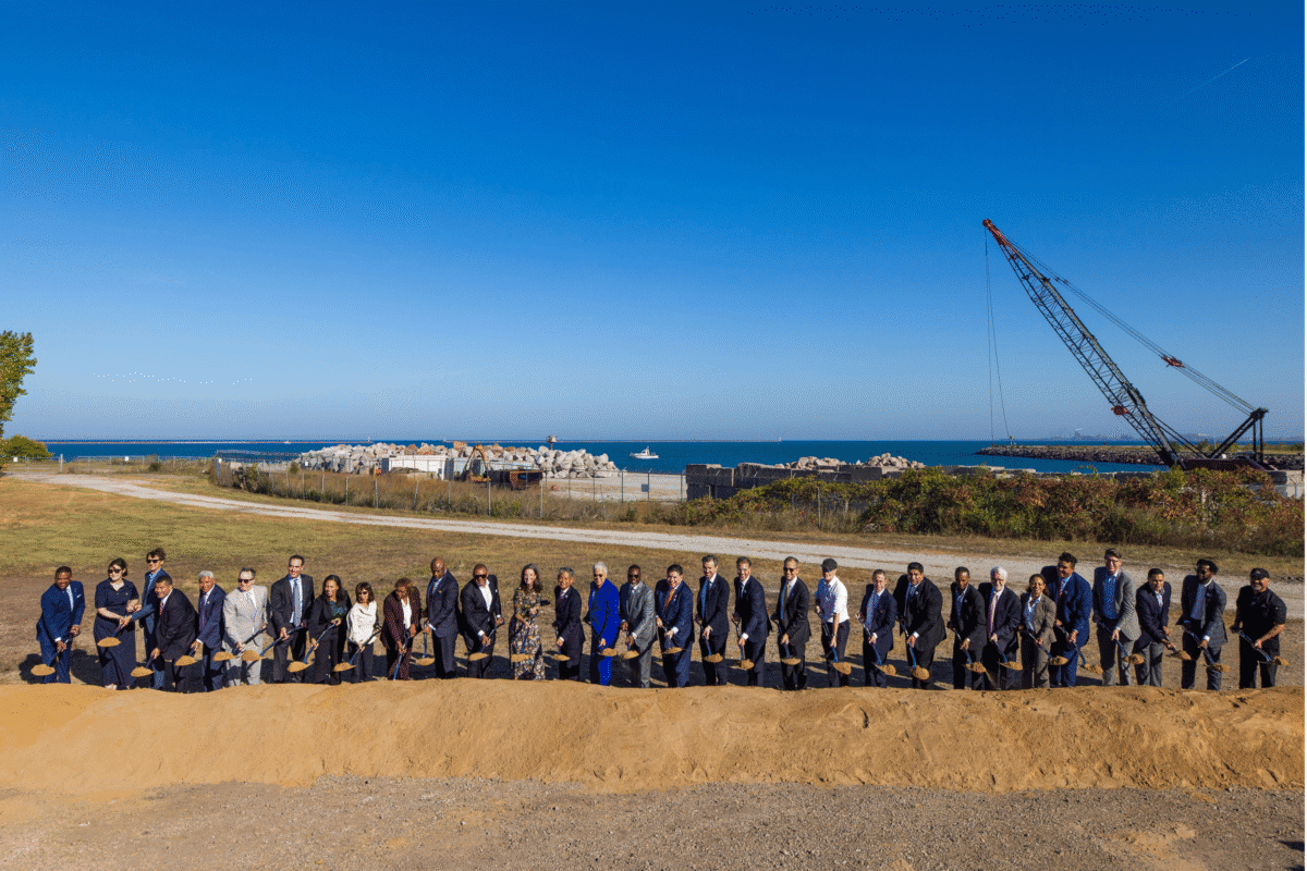 A large group of government, community and industry leaders stands side by side holding shovels for the IQMP groundbreaking ceremony.