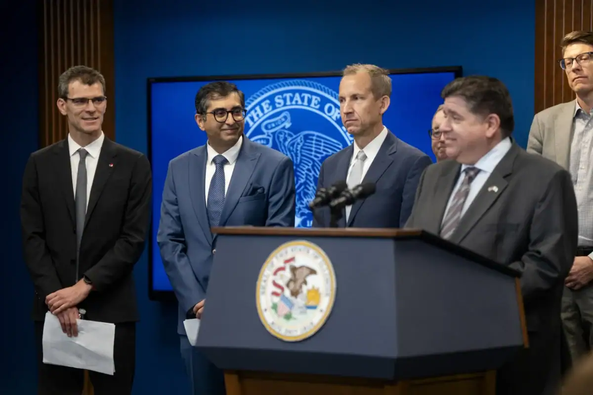 Governor JB Pritzker, IQMP CEO Harley Johnson and Pasqal executives stand behind a podium at Pasqal's announcement as an IQMP tenant