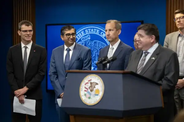 Governor JB Pritzker, IQMP CEO Harley Johnson and Pasqal executives stand behind a podium at Pasqal's announcement as an IQMP tenant